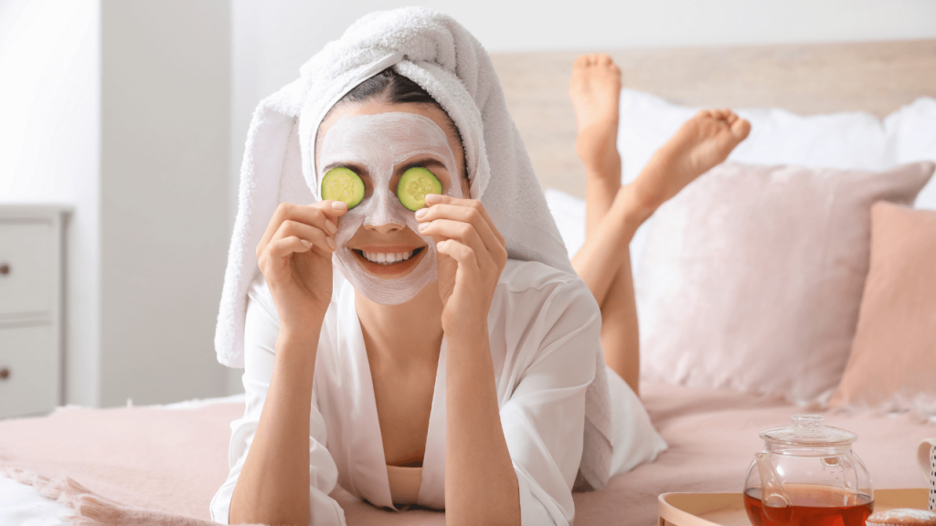 A girl on a bed with cucumber slices on her eyes and with a skincare mask on her face